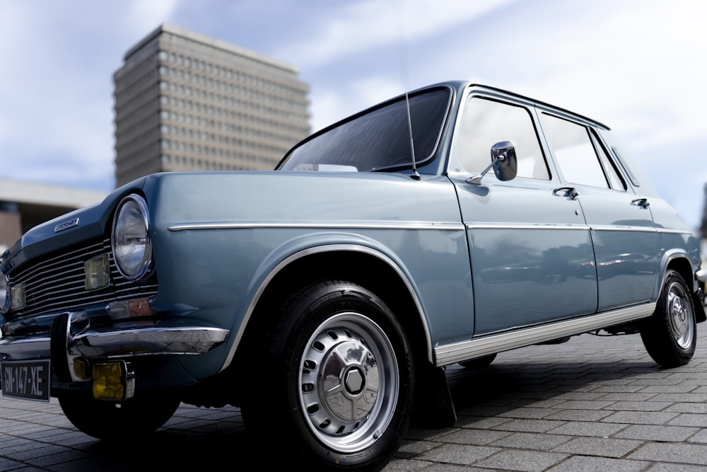 a blue car parked in front of a tall building