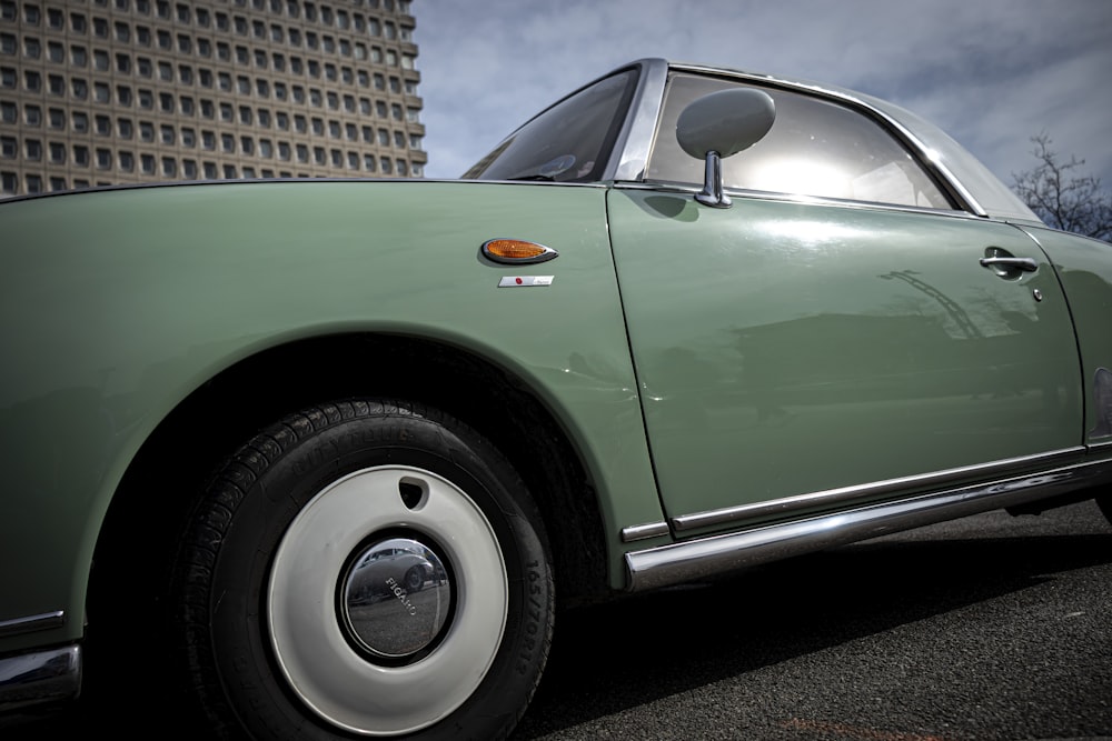 a green car parked in front of a tall building