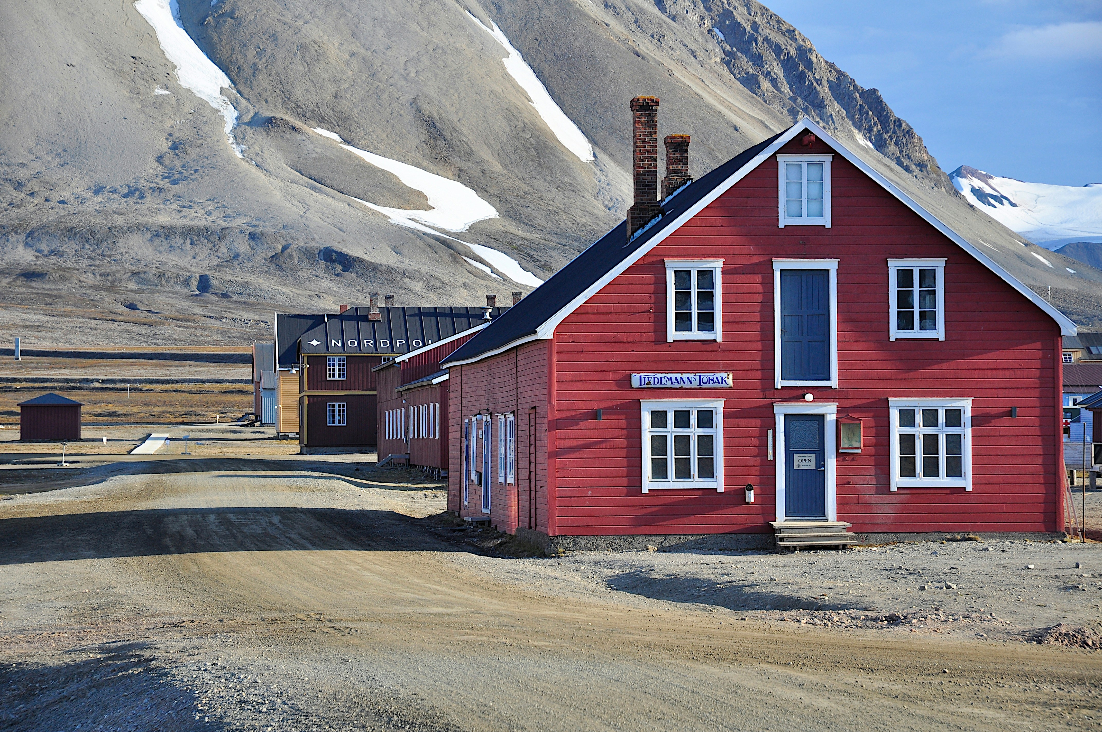 a red building sitting on the side of a dirt road