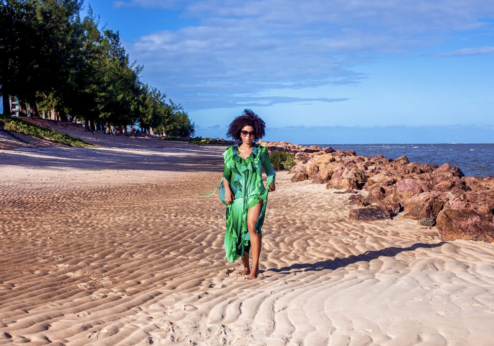 a woman in a green dress walking on a beach