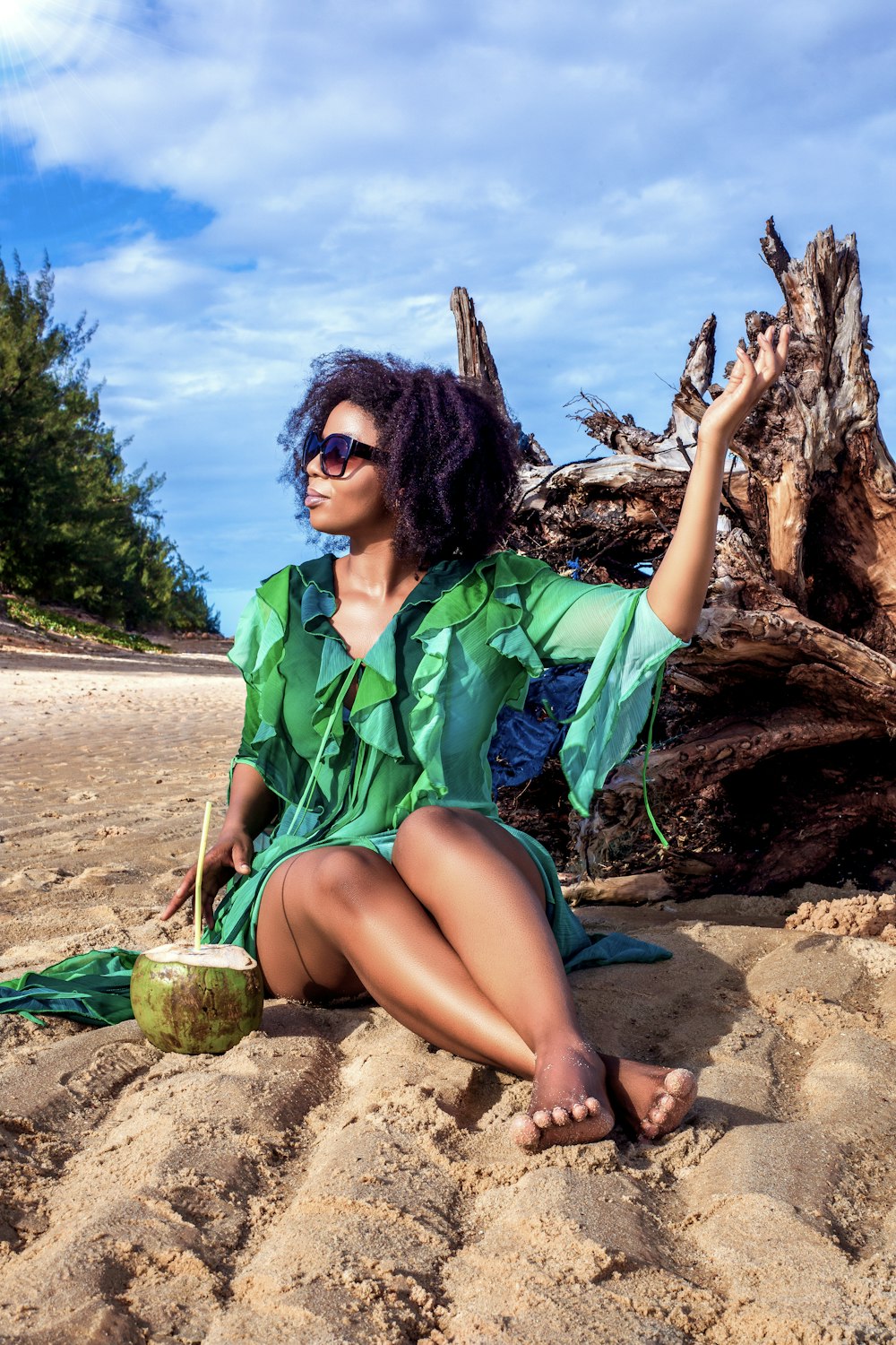 a woman in a green dress sitting on a beach