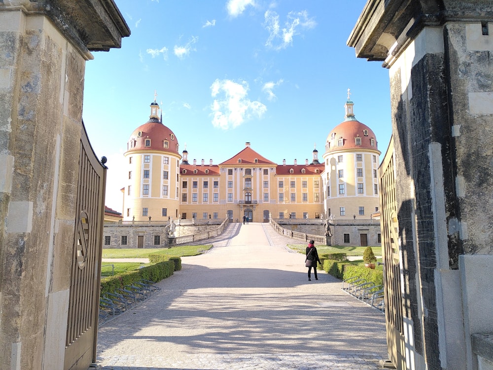 a person walking down a road in front of a large building