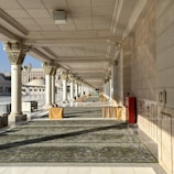 a long hallway with columns and a rug on the floor