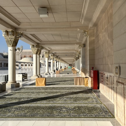 a long hallway with columns and a rug on the floor