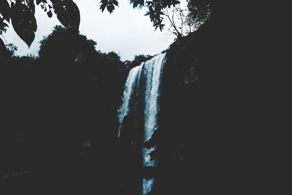 a large waterfall with a person standing in front of it