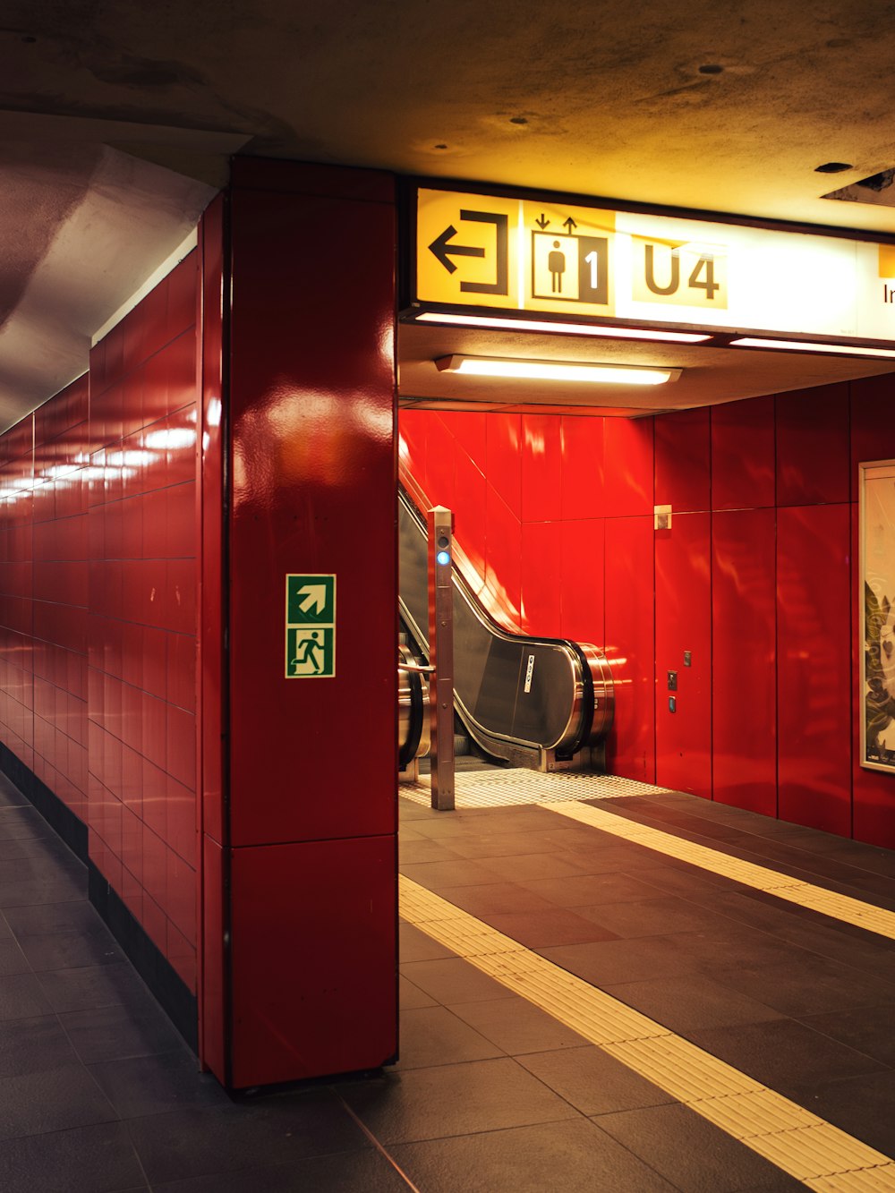 an escalator in a subway station with a red wall