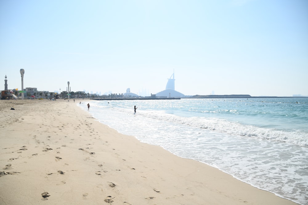 a sandy beach with people walking on it