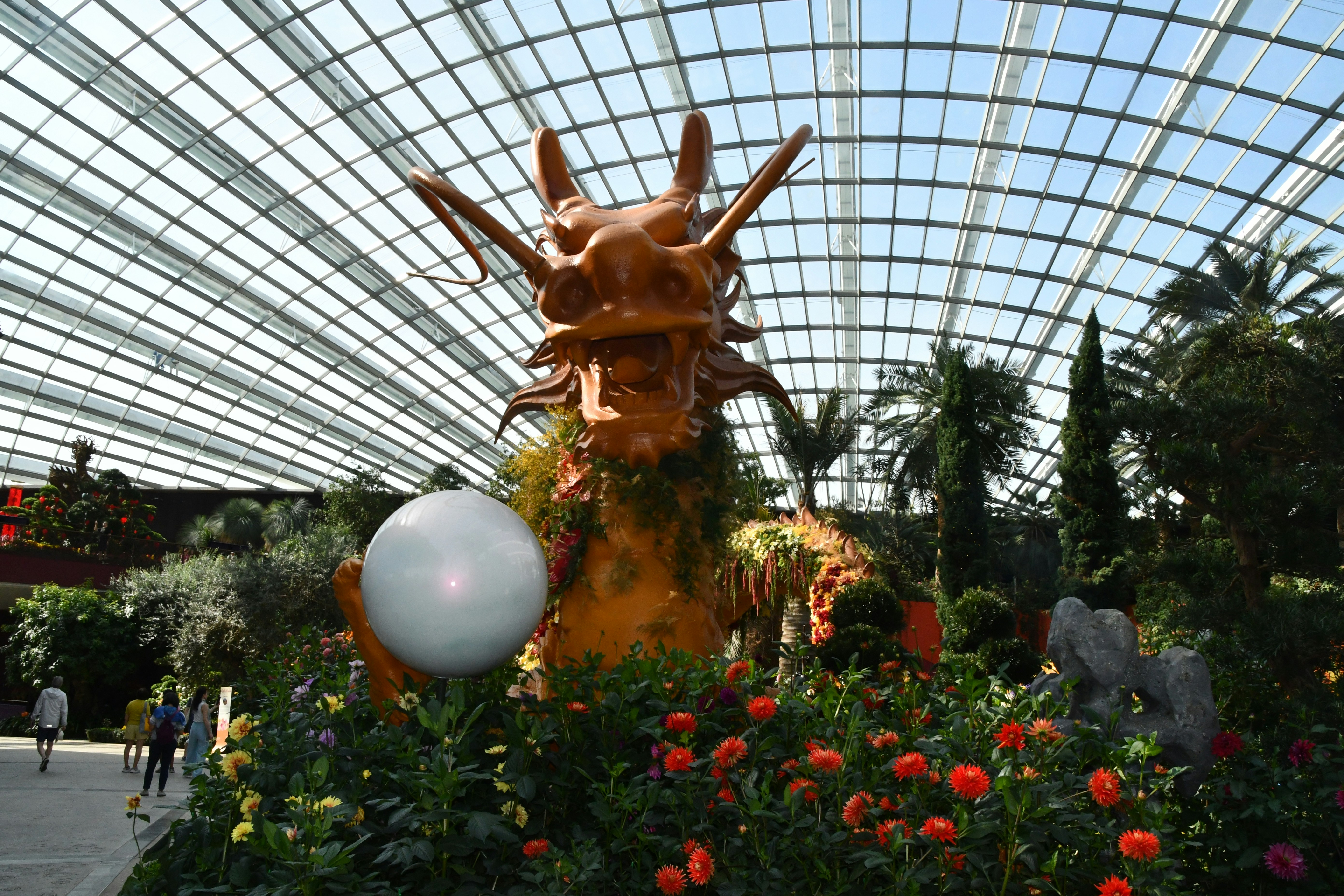uma estátua de um dragão em um jardim de flores