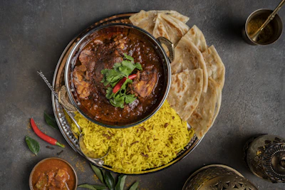 a bowl of curry, rice and pita bread