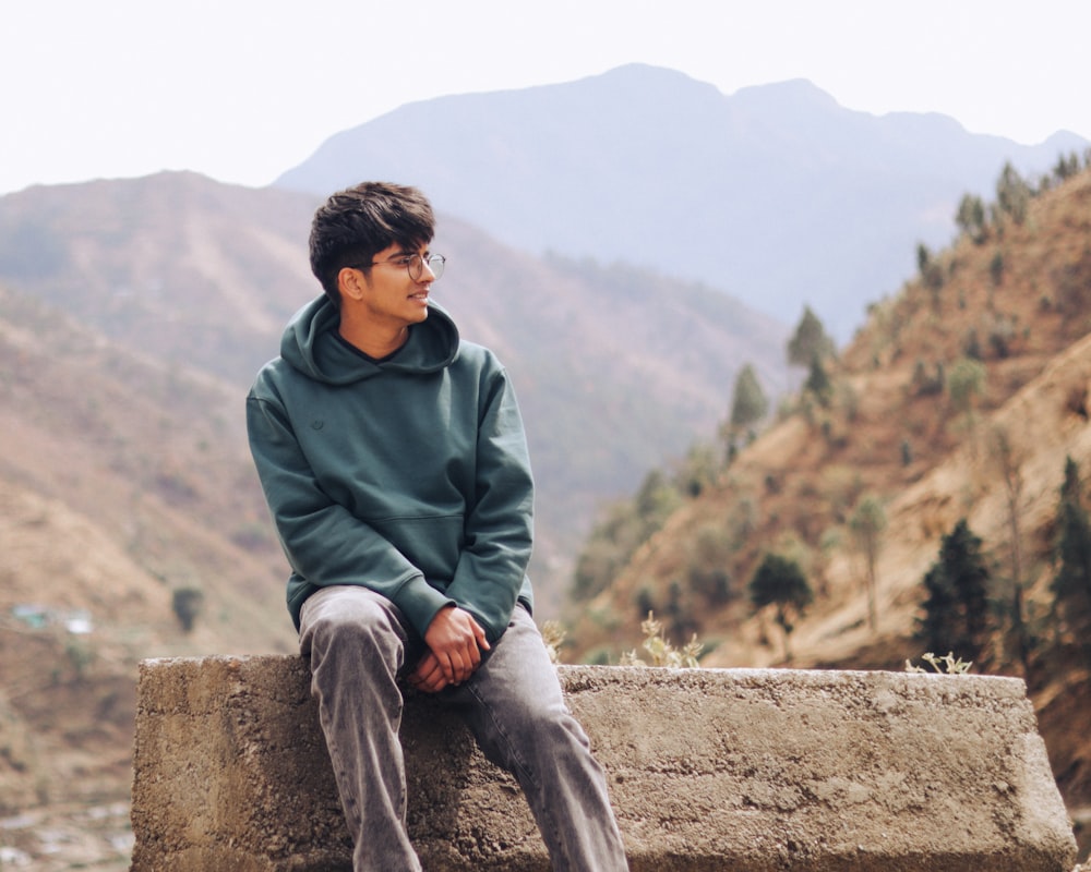 a man sitting on top of a stone wall
