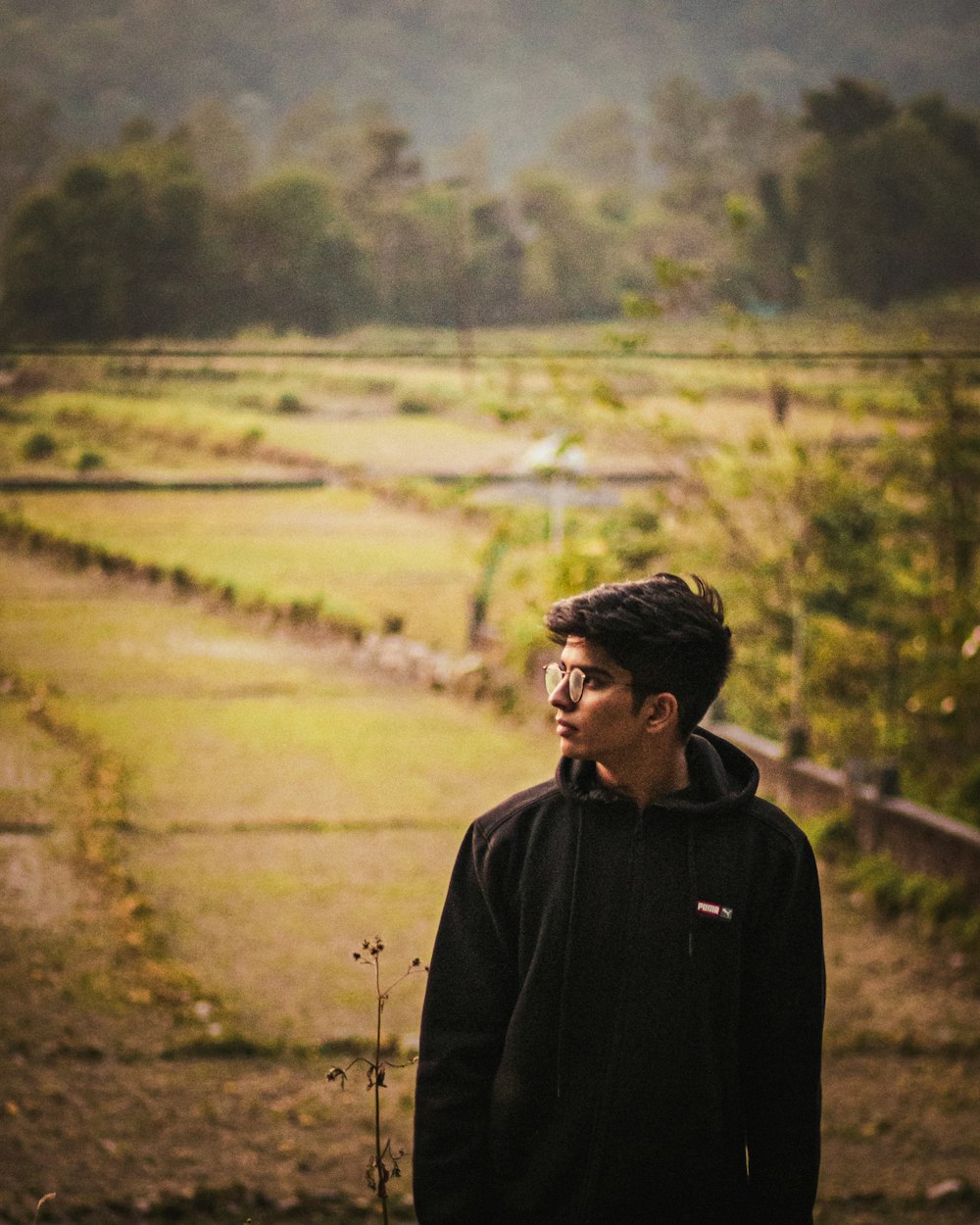 a man standing in a field with trees in the background