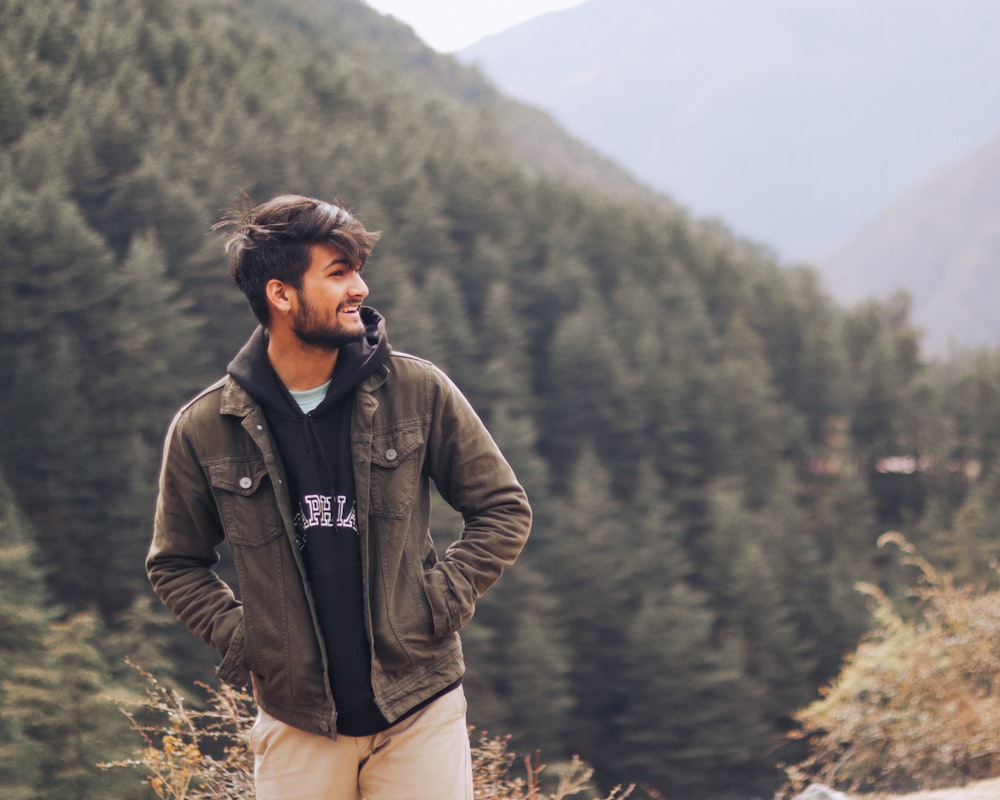 a man standing on top of a mountain next to a forest