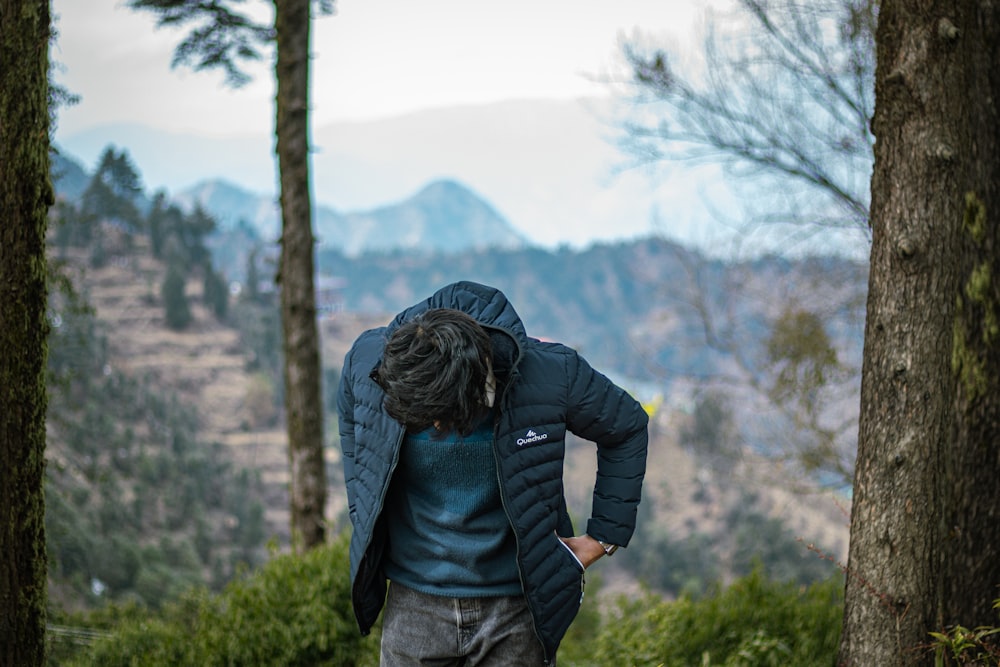 a man with his back to the camera in the woods