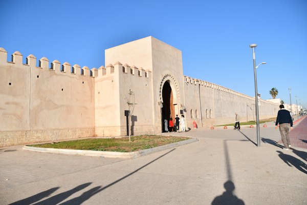 A man walking down a street past a tall building — Agadir, Morocco