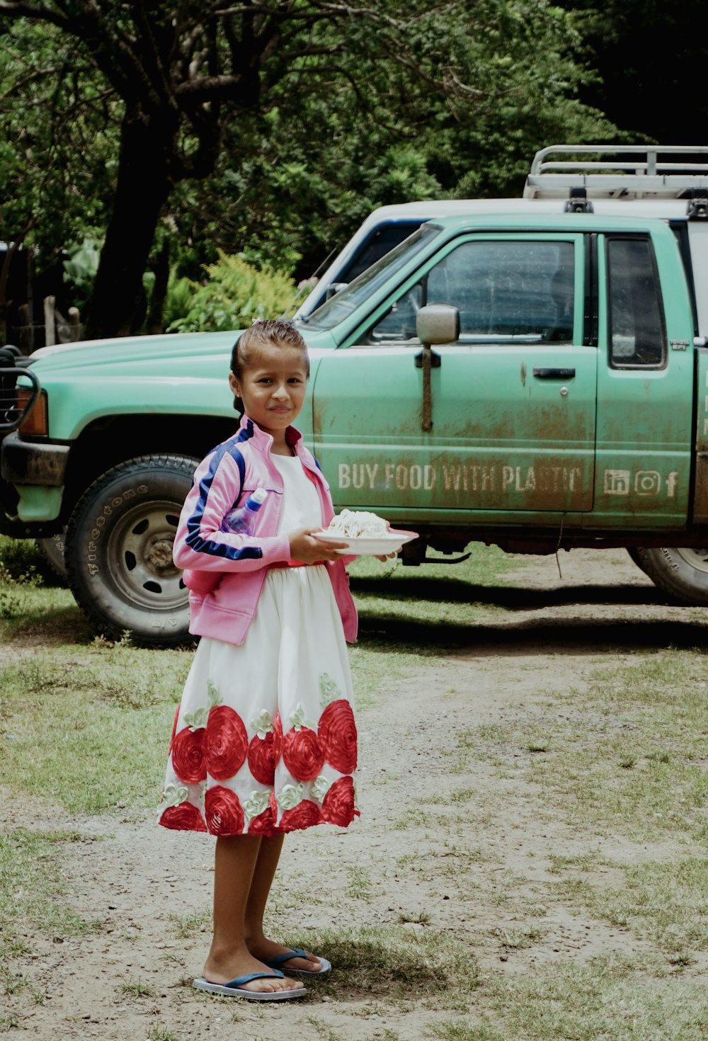 a young girl holding a plate of food in front of a truck