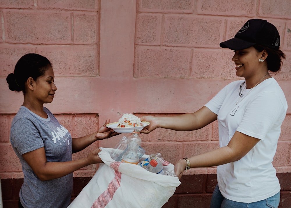 a woman handing another woman a plate of food