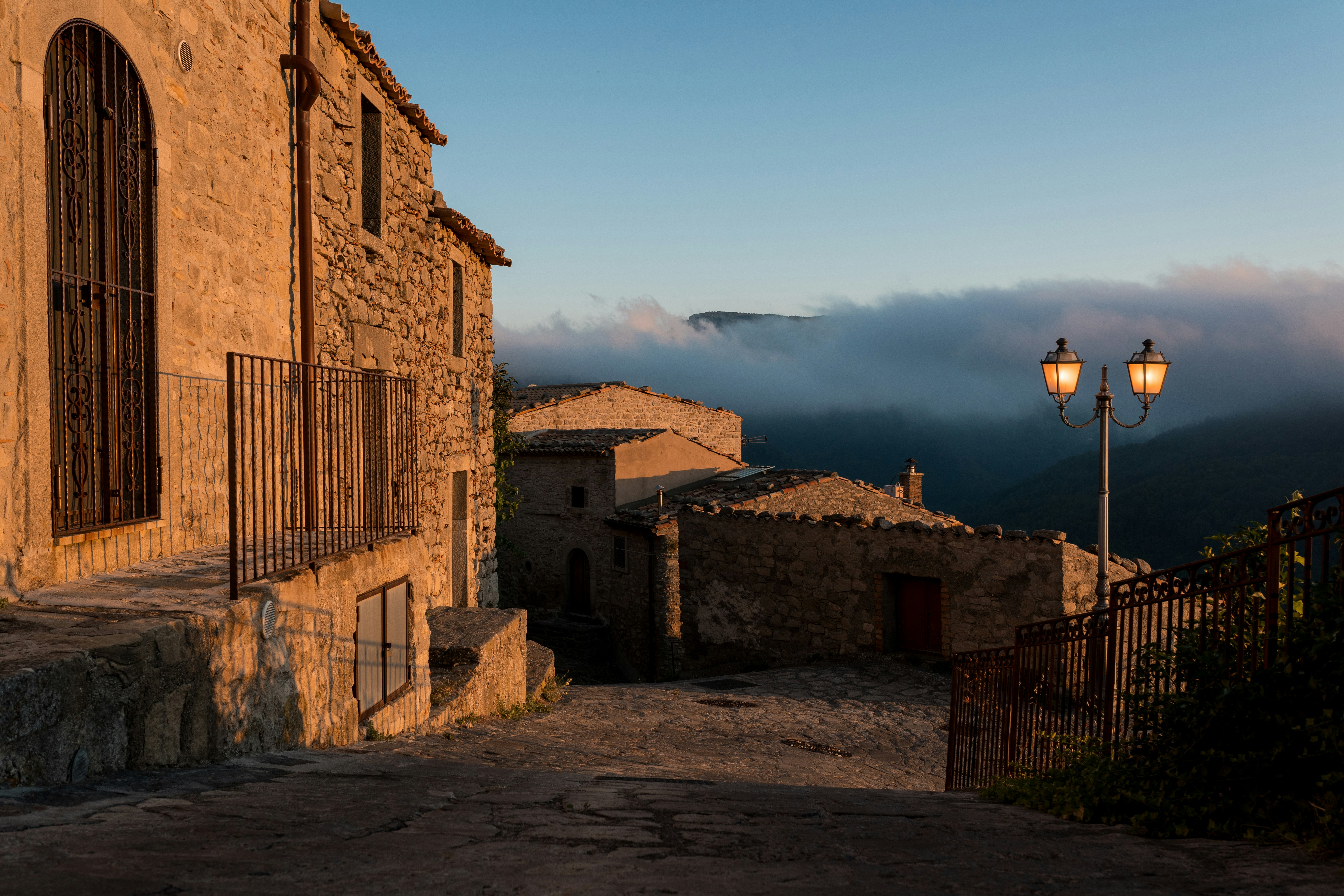 a cobblestone street leading to a stone building, 