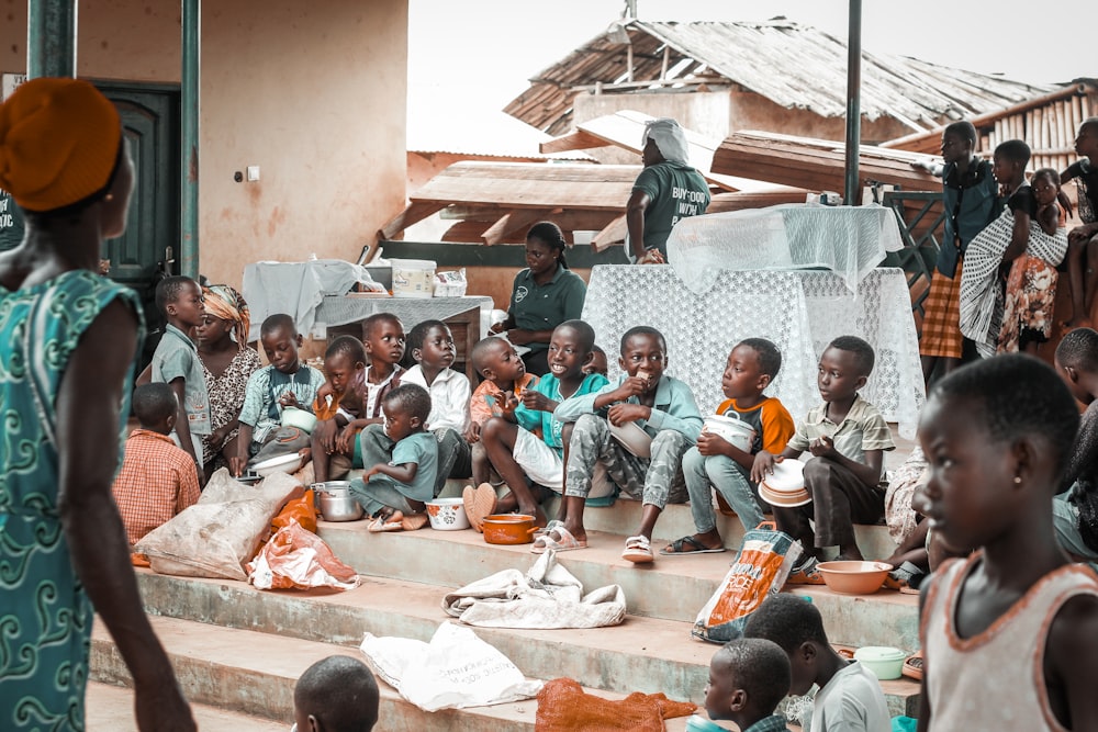um grupo de crianças sentadas em degraus em frente a um prédio