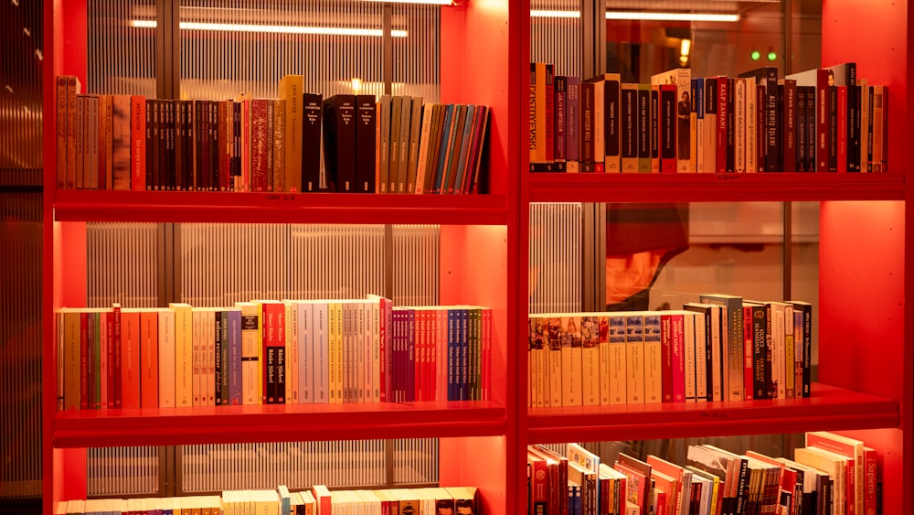 a red book shelf filled with lots of books