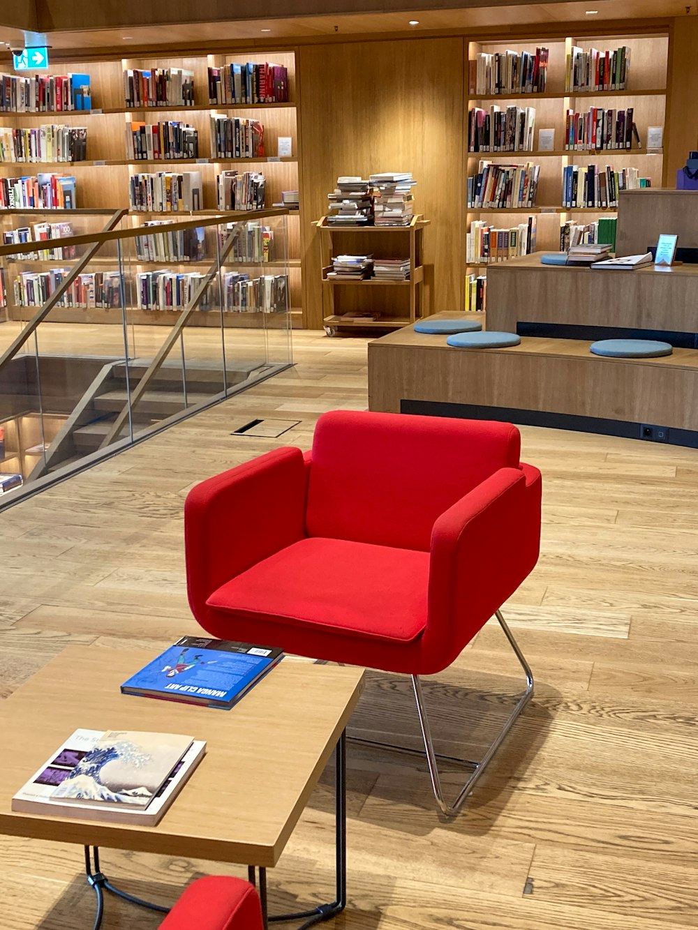a red chair sitting in a library next to a coffee table