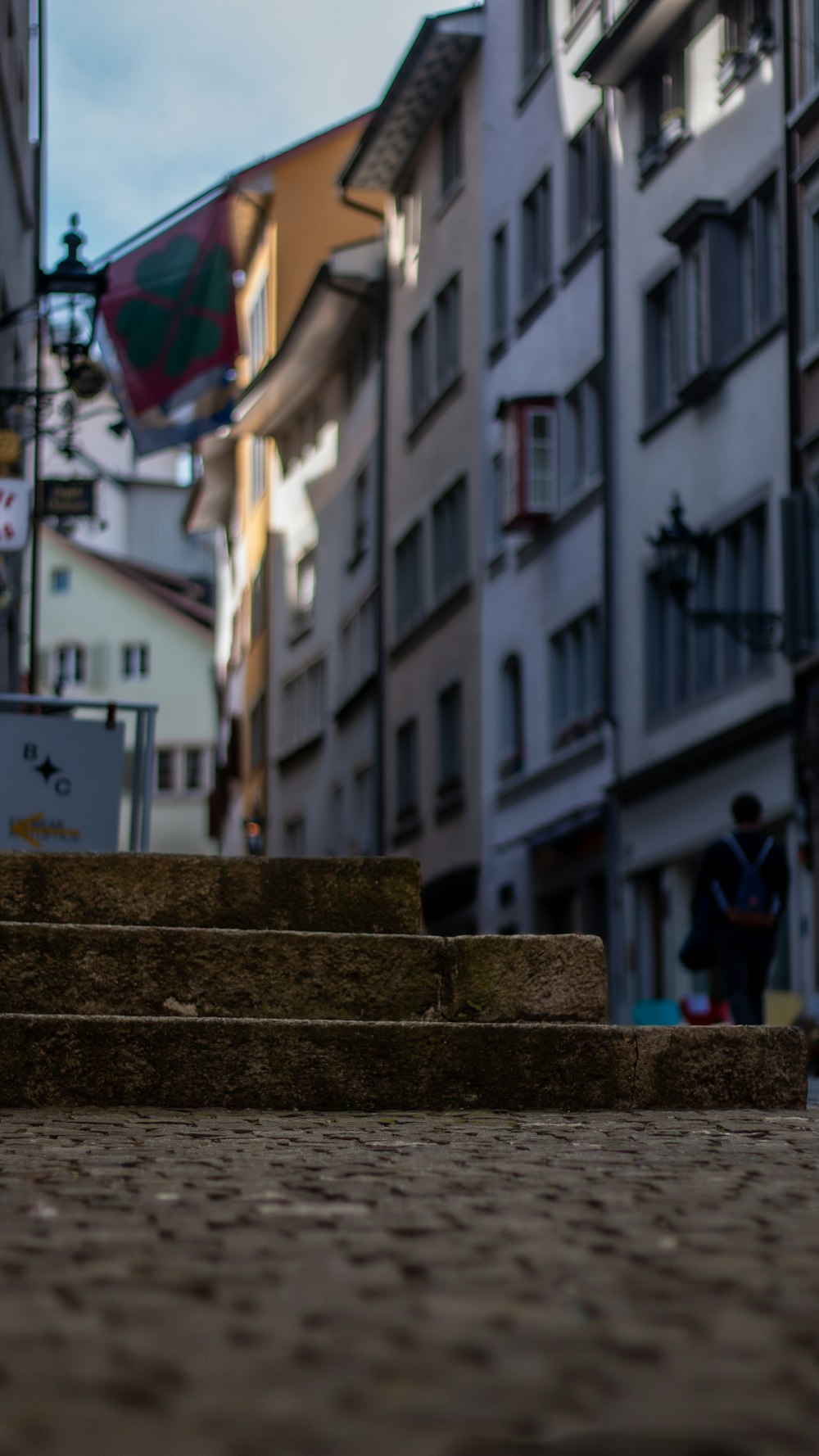 a person walking down a street next to tall buildings