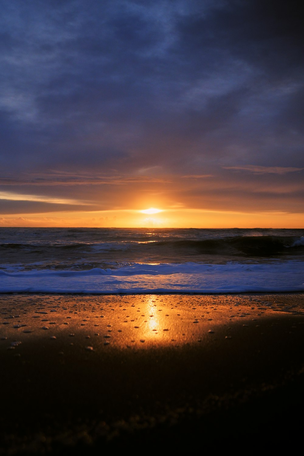 the sun is setting over the ocean on the beach