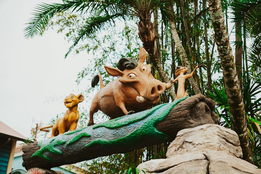 a statue of a pig and a dog on top of a log