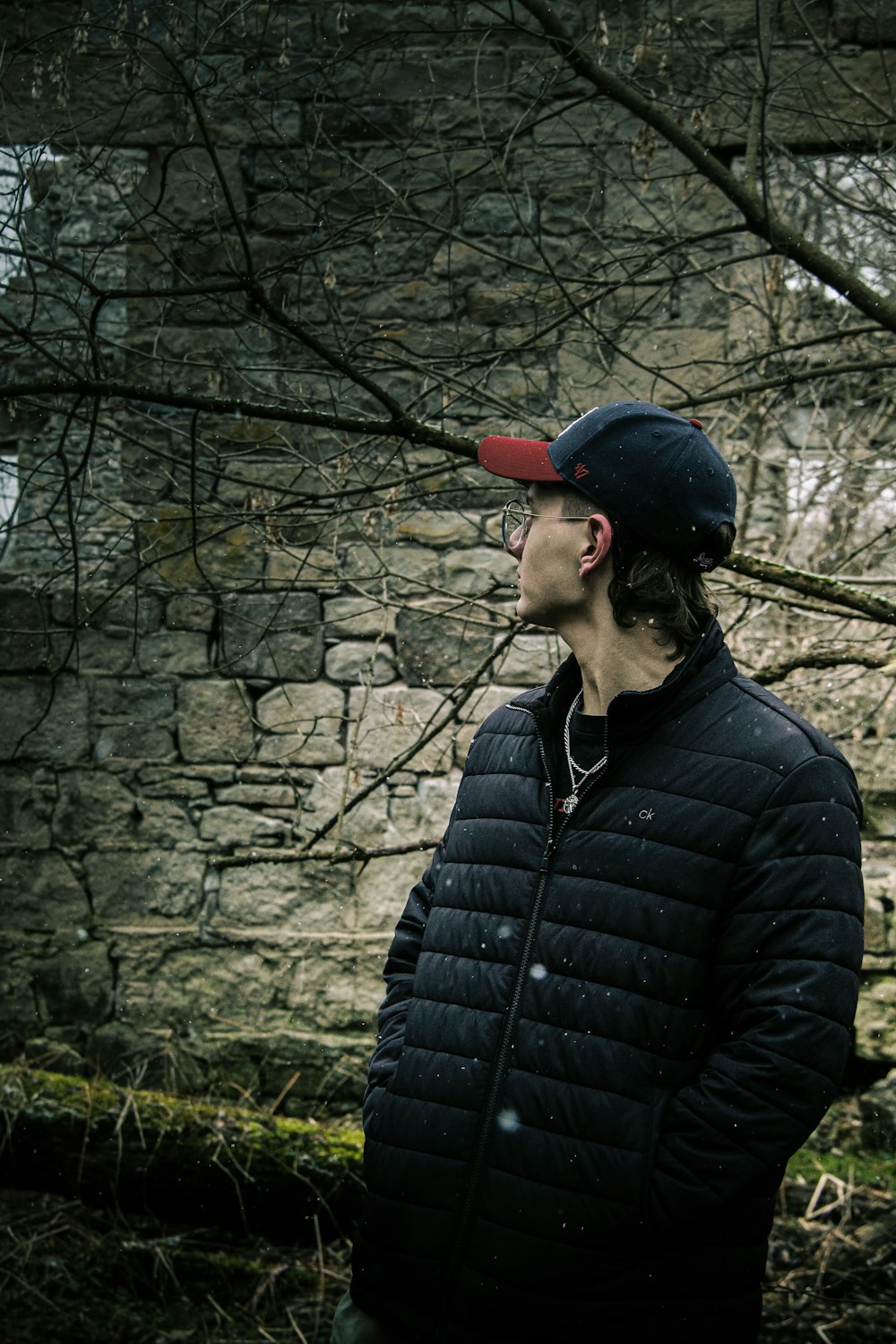 a man standing in front of a stone wall