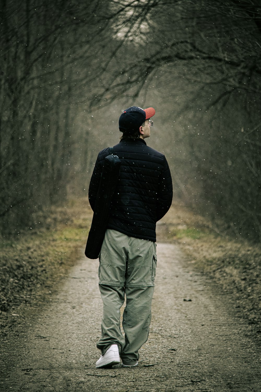 a man walking down a dirt road in the woods