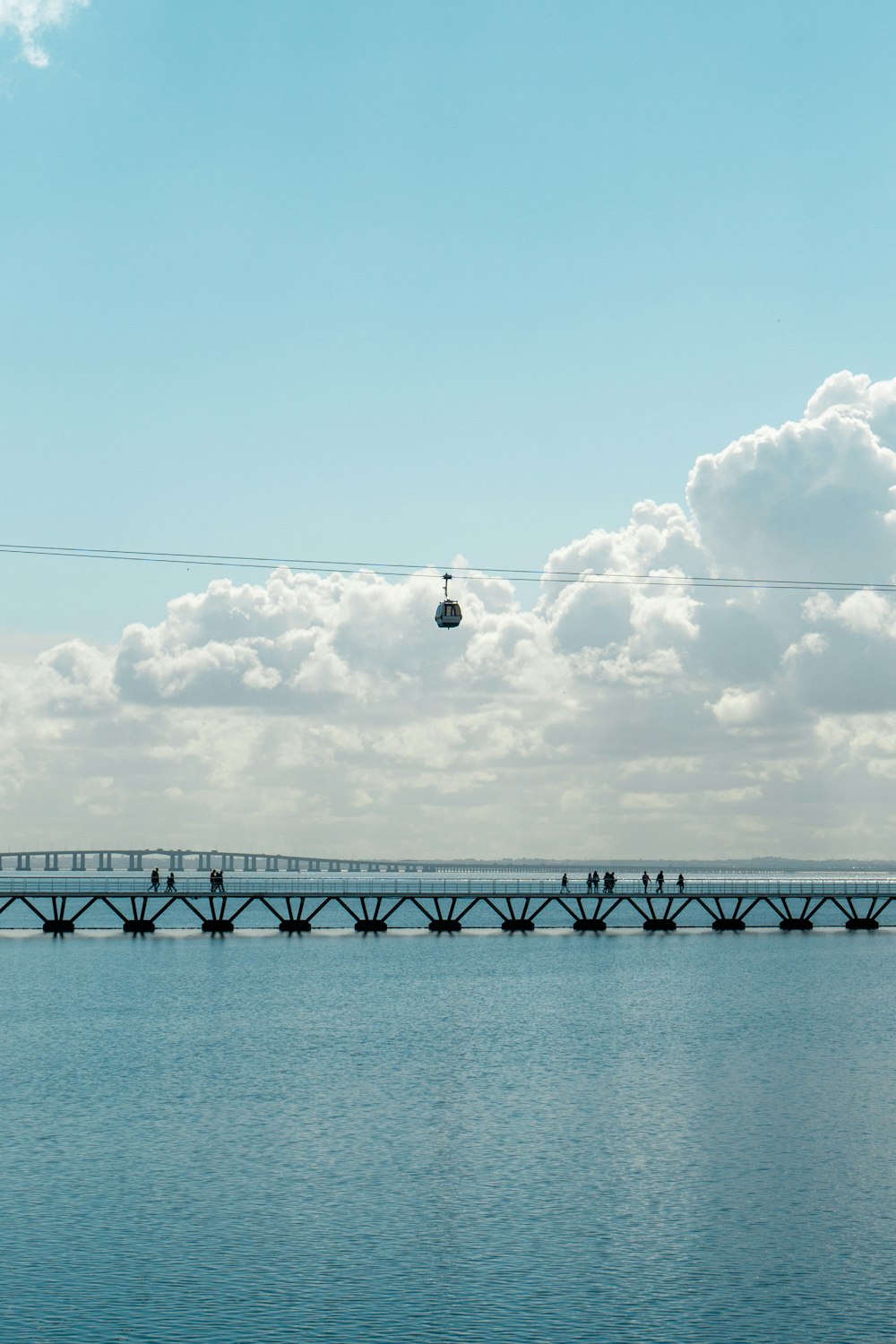 a bridge over a body of water under a cloudy blue sky