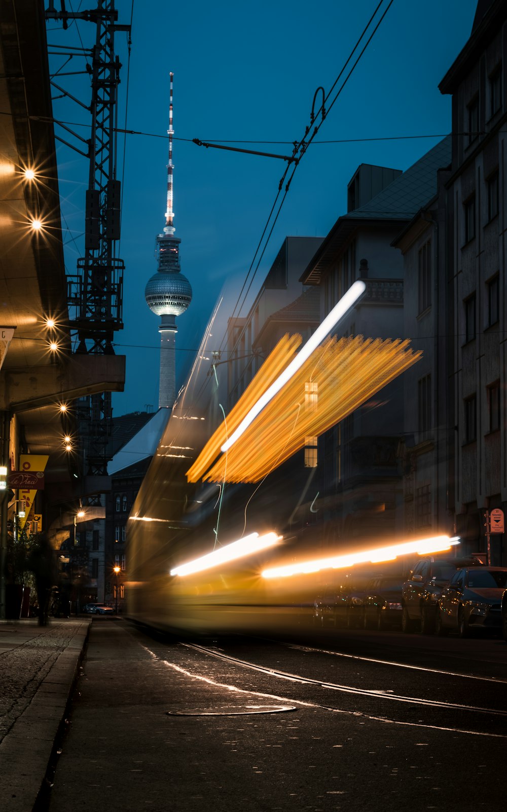 Ein Zug, der eine Straße neben einem hohen Gebäude entlangfährt