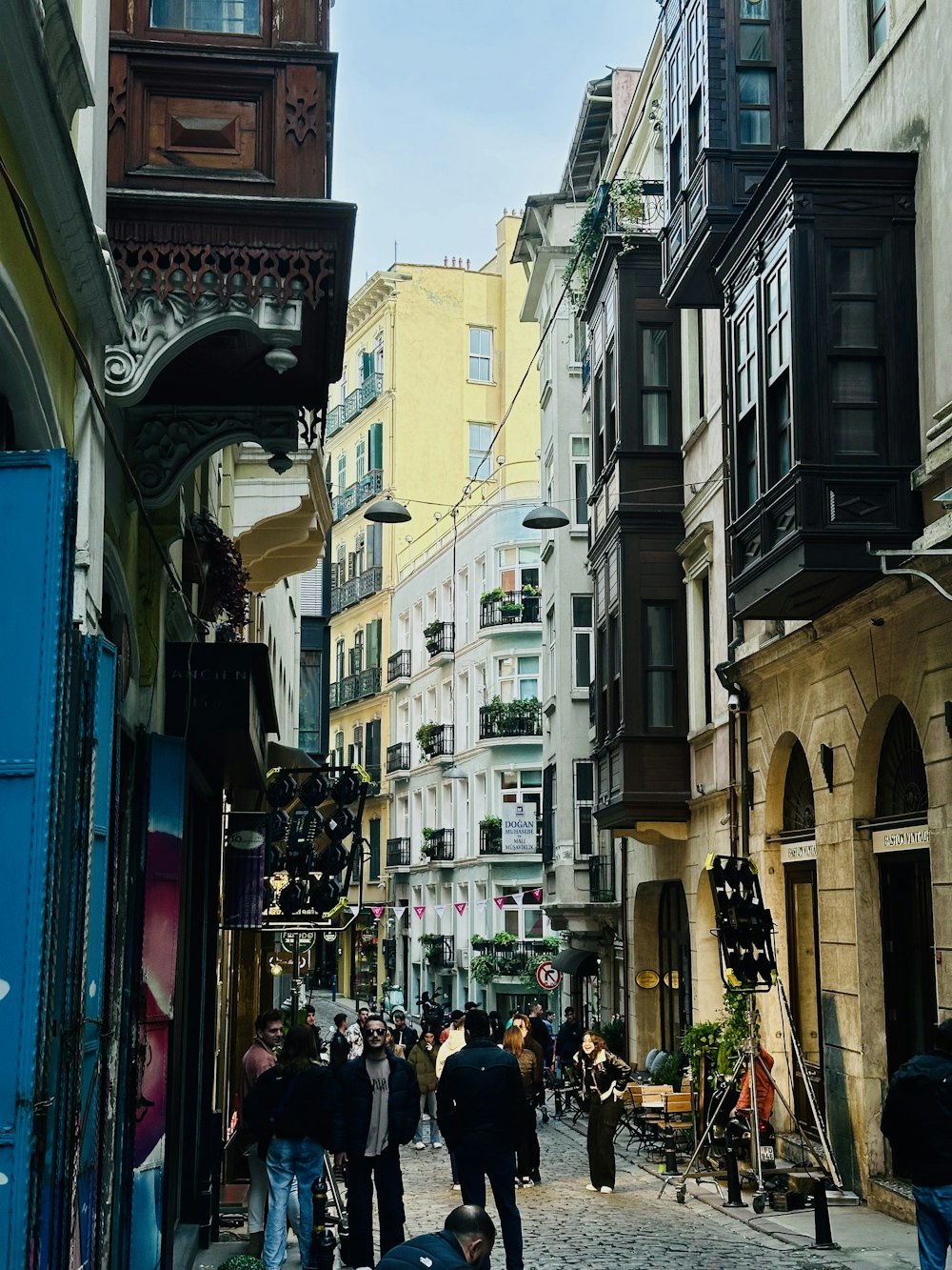 a group of people walking down a street next to tall buildings