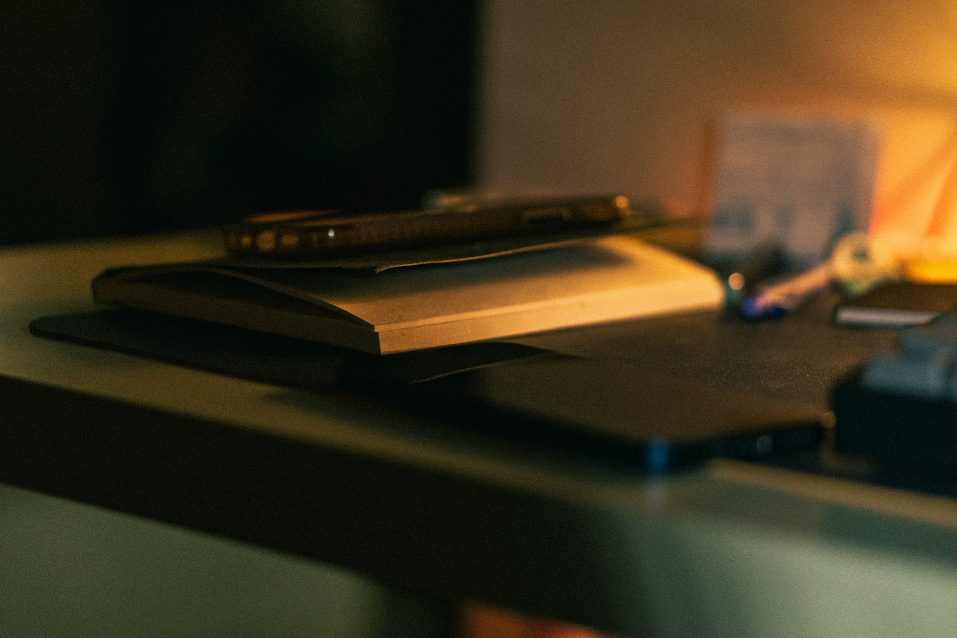 a desk with a notebook, pen, and other items on it