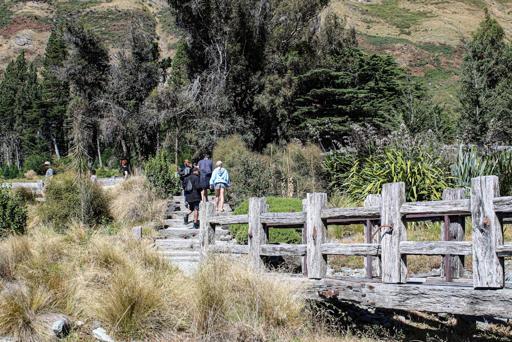 a group of people walking across a wooden bridge