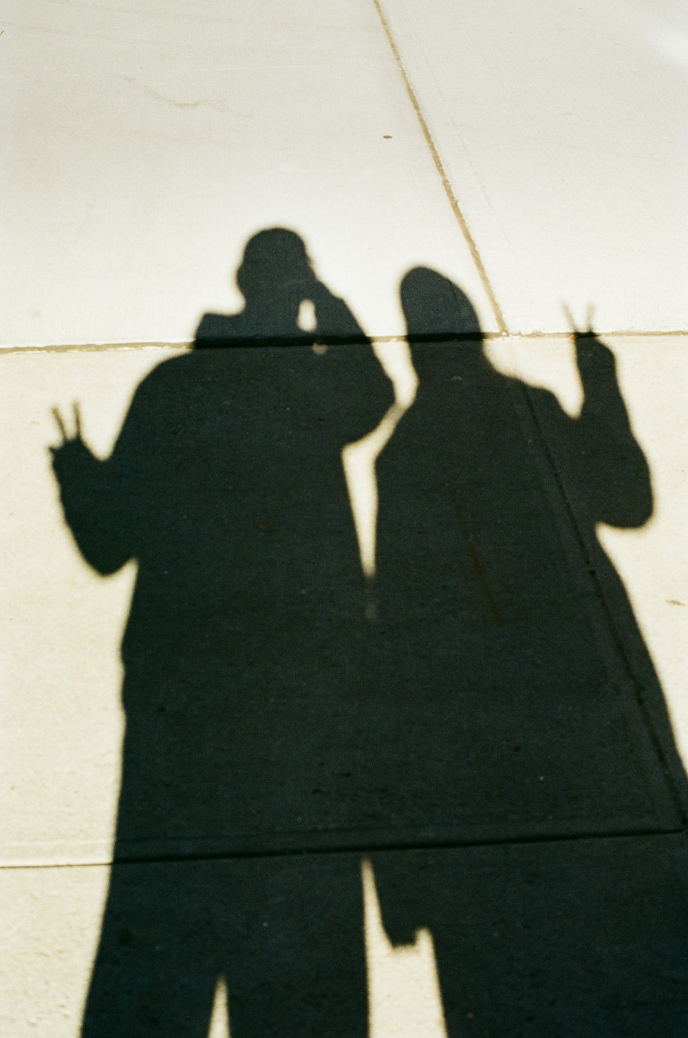 a shadow of a man and a woman on a sidewalk