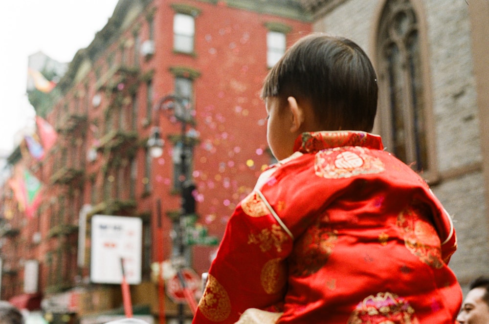 a little boy in a red and gold chinese outfit