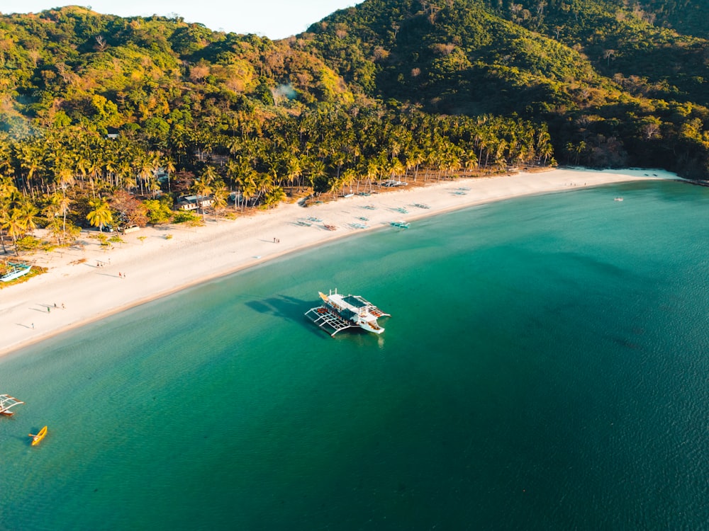 an aerial view of a beach with a boat in the water