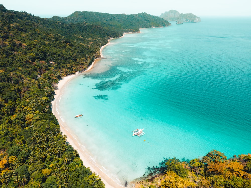 an aerial view of a beach with a boat in the water