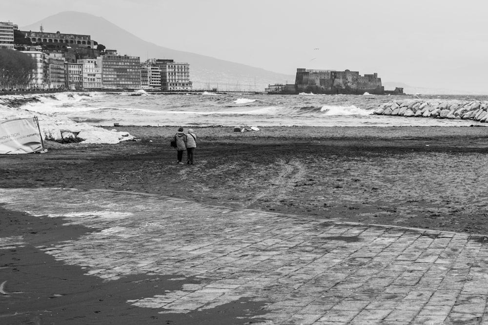 a man standing on top of a beach next to the ocean