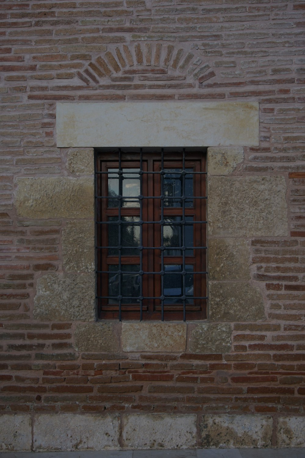 una pared de ladrillo con una ventana y rejas