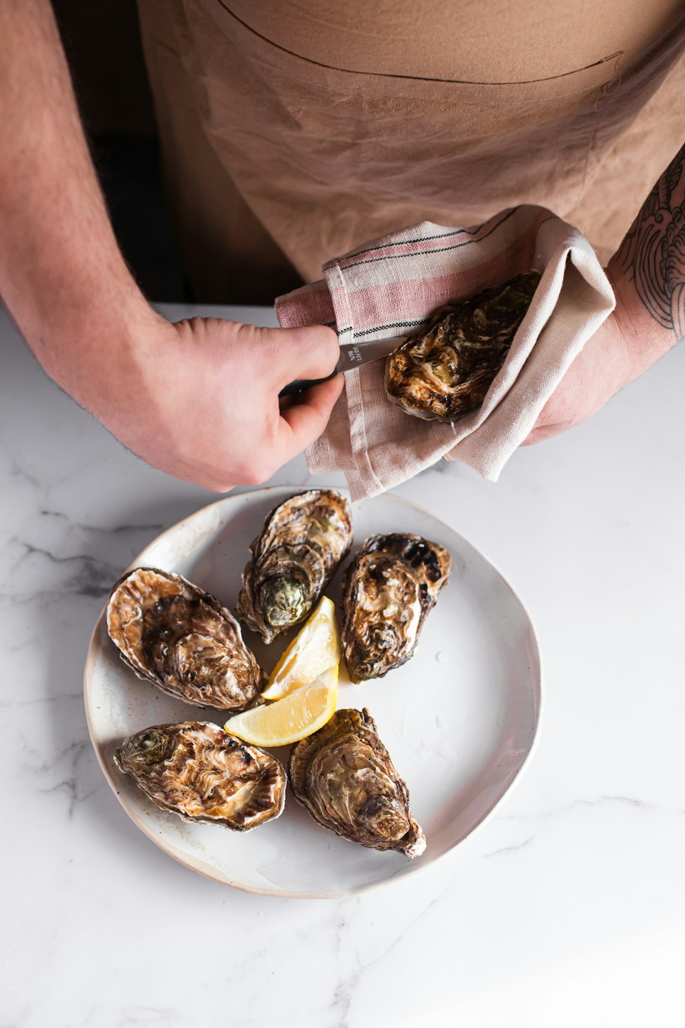 a person holding a plate of oysters on a table