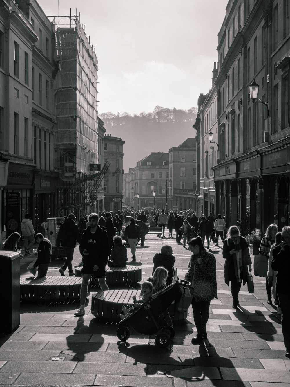 a group of people walking down a street next to tall buildings