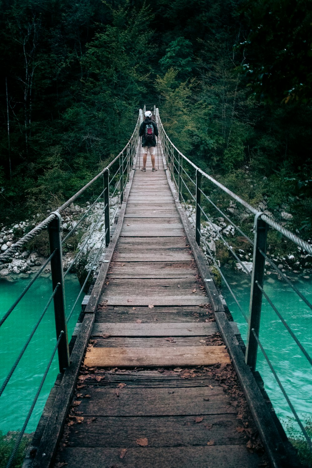 a person walking across a bridge over a river