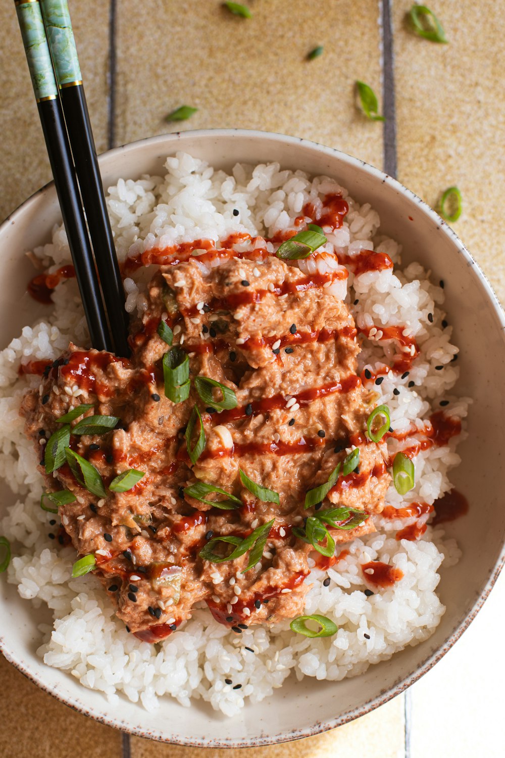 a bowl filled with rice and meat with chopsticks