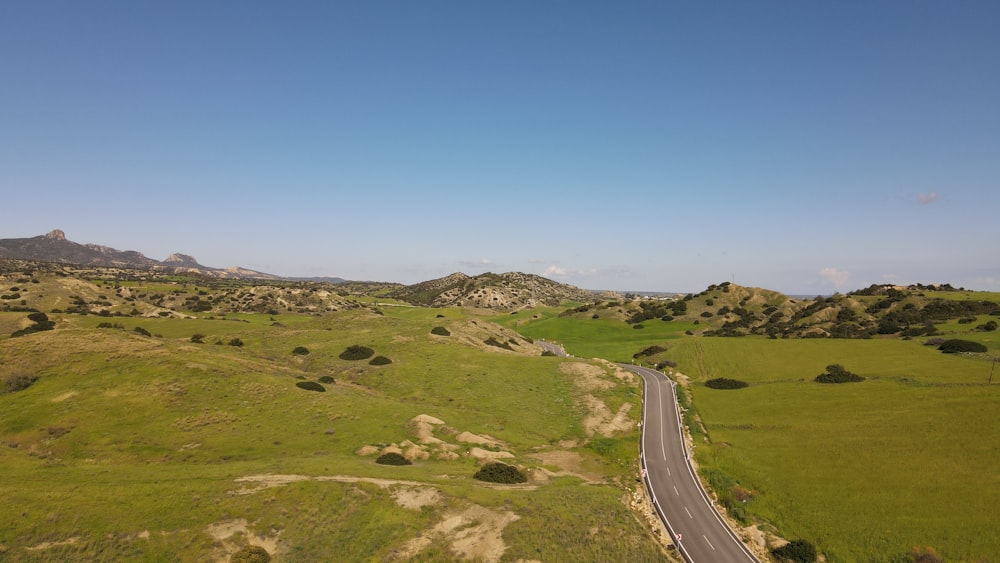 an aerial view of a road in the middle of a green field