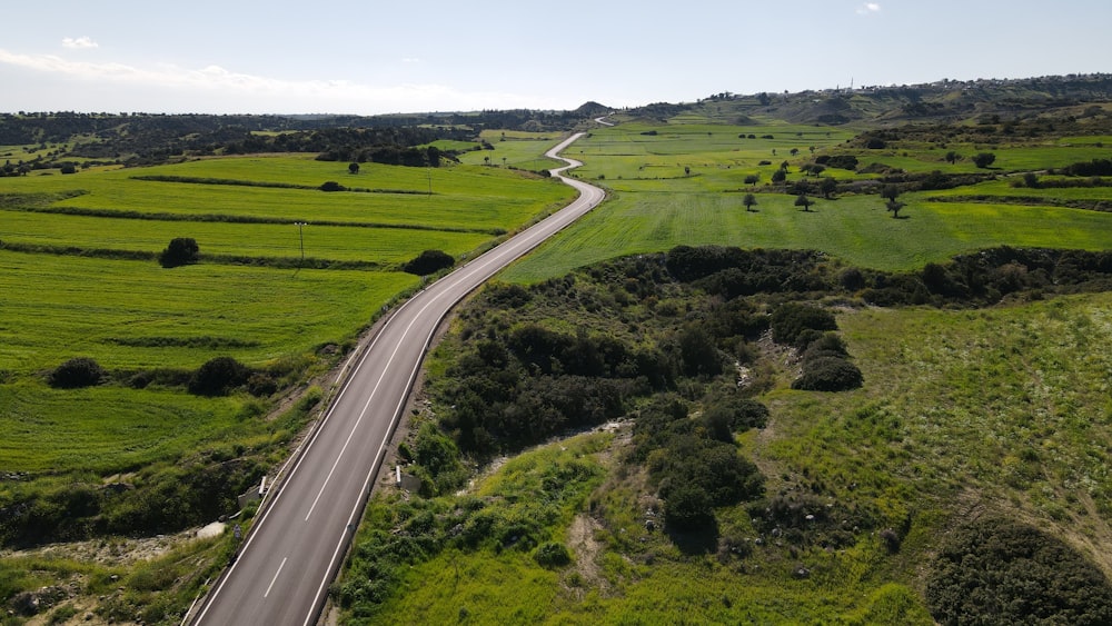 an aerial view of a road winding through a green field