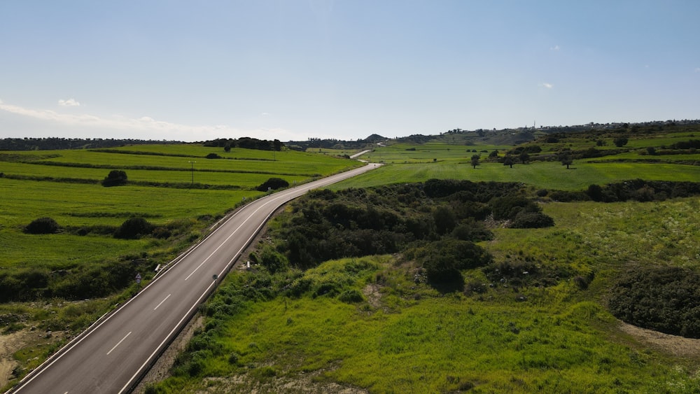 an aerial view of a highway in the middle of a green field