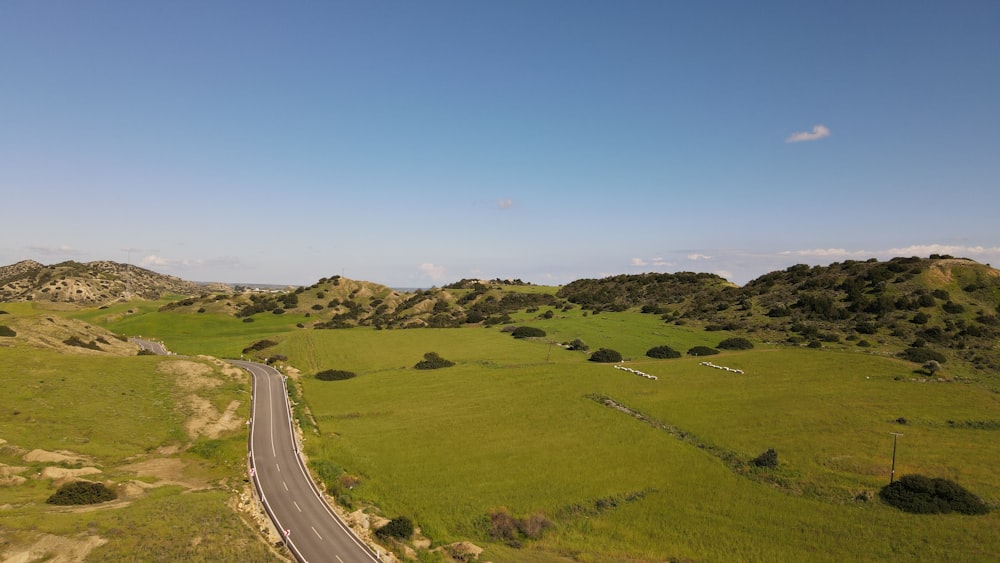 an aerial view of a road in the middle of a green field