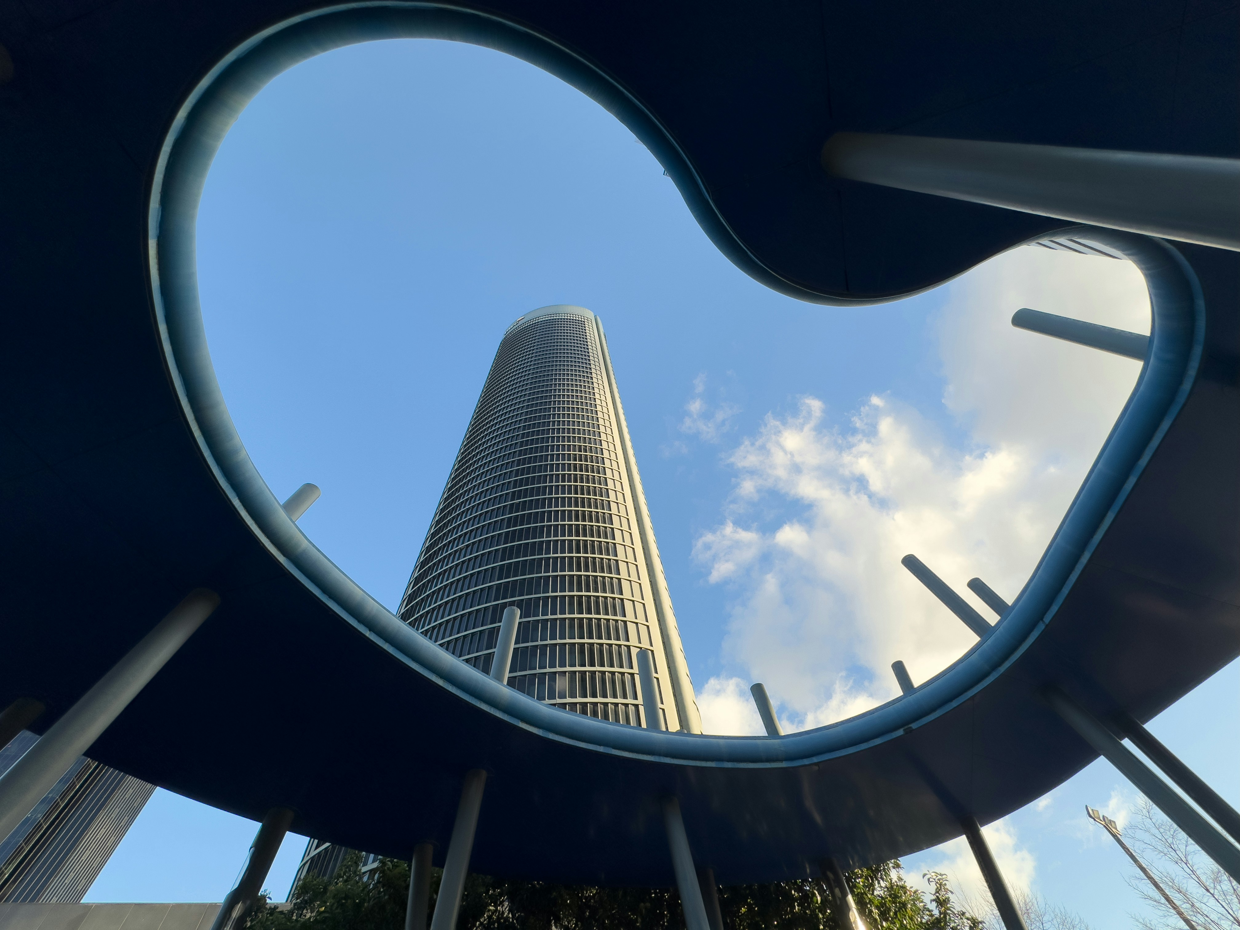 A tall building seen through a circular window photo – Free Torre pwc ...