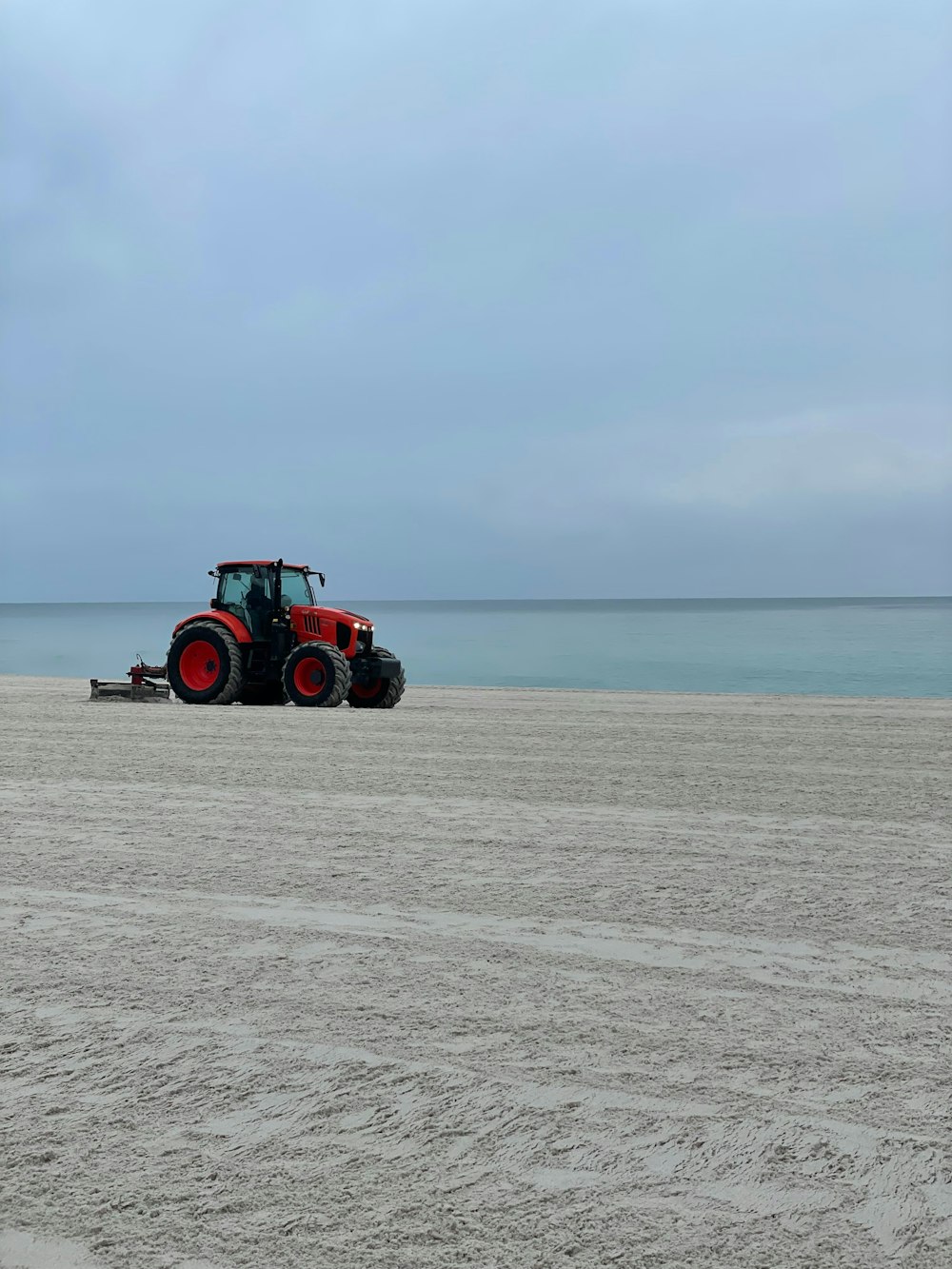 a tractor is parked on a beach near the ocean